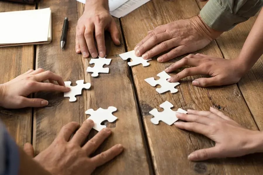 Hands working together on puzzle pieces. Hands working together on puzzle pieces.