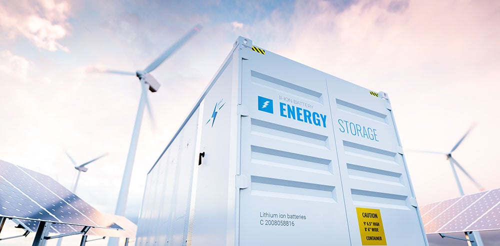 Battery energy storage containers with wind turbines in background.
