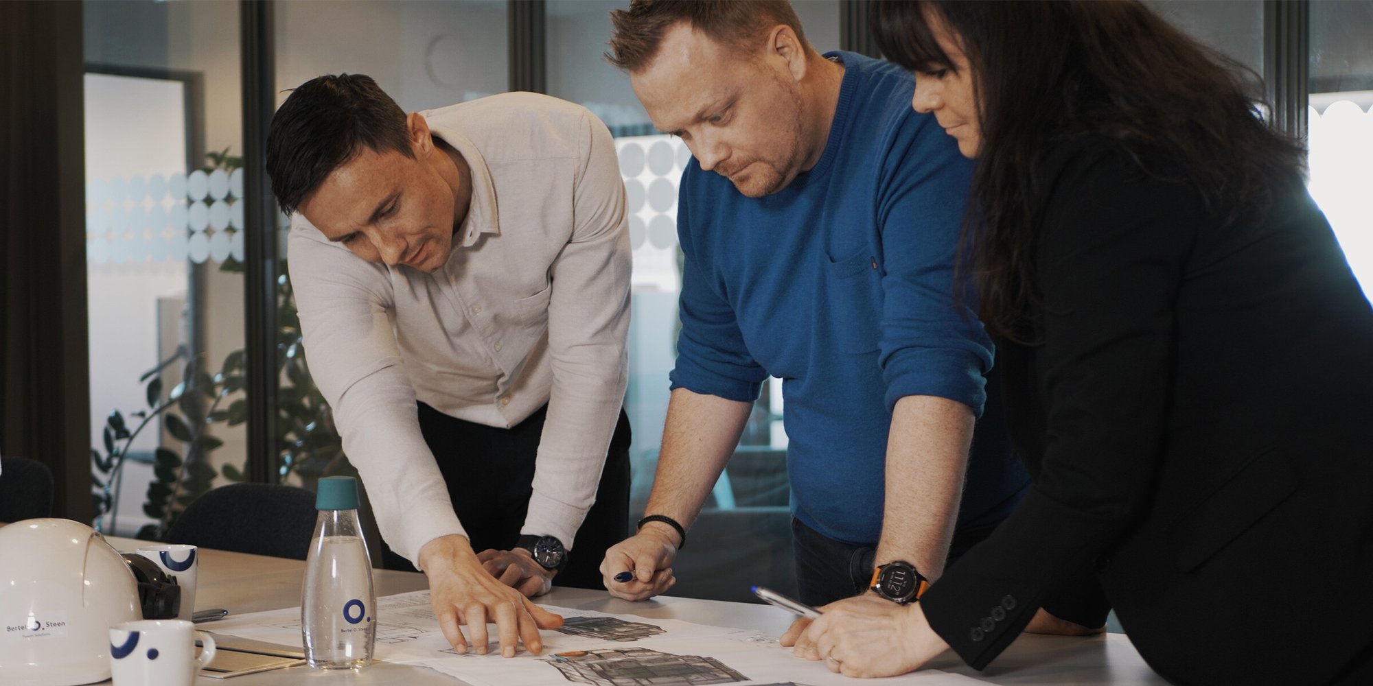 Team of three people collaborating over documents in office. Team of three people collaborating over documents in office.