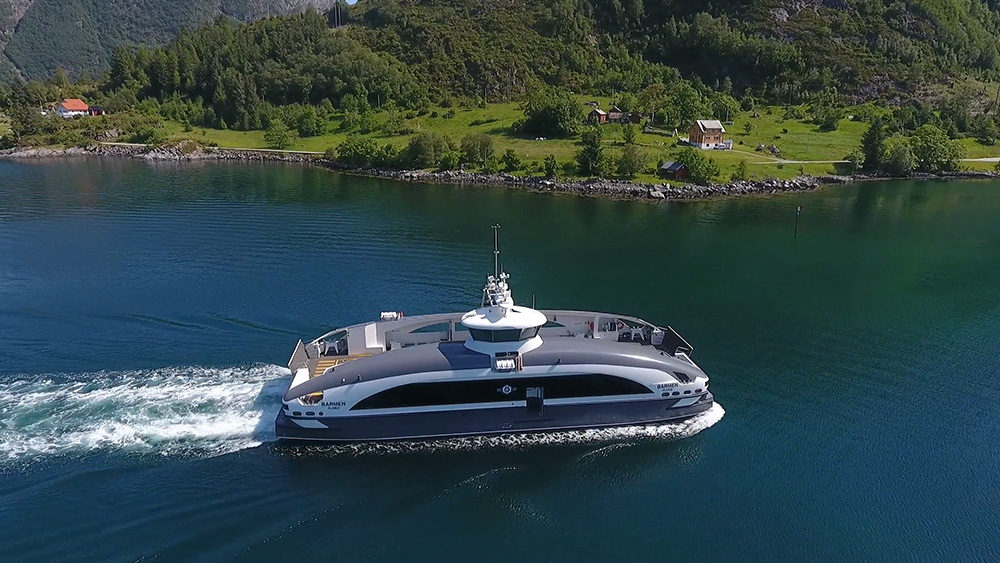 Modern ferry sailing on fjord with green hills in background. Modern ferry sailing on fjord with green hills in background.